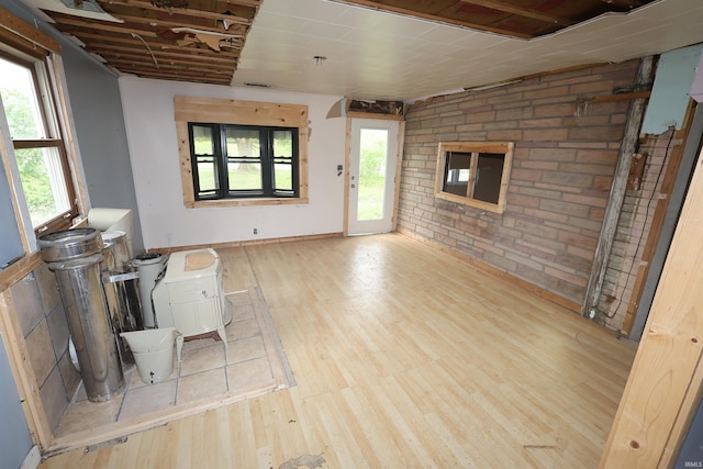 unfurnished living room with brick wall and wood finished floors