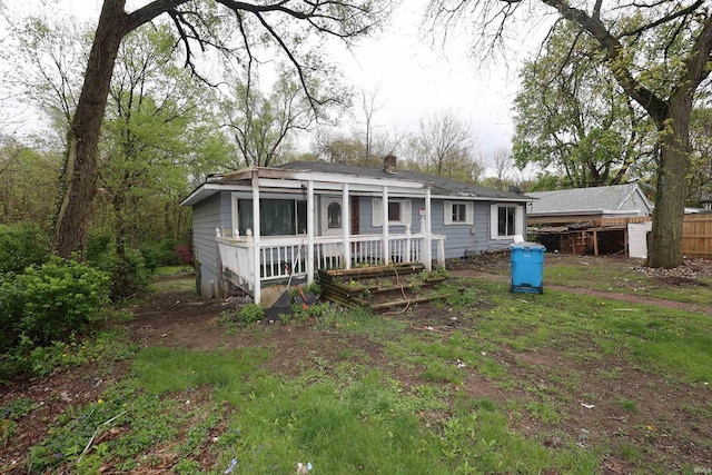 rear view of house with a porch, fence, and a chimney