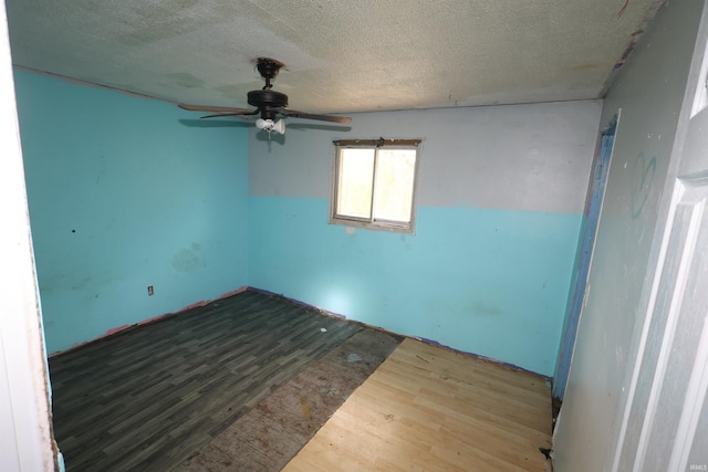 empty room featuring a ceiling fan, a textured ceiling, and wood finished floors