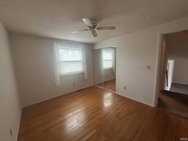 unfurnished bedroom featuring visible vents, a closet, baseboards, ceiling fan, and light wood finished floors