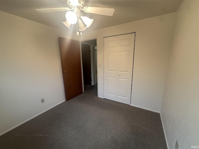 unfurnished bedroom featuring baseboards, a ceiling fan, a closet, and dark colored carpet