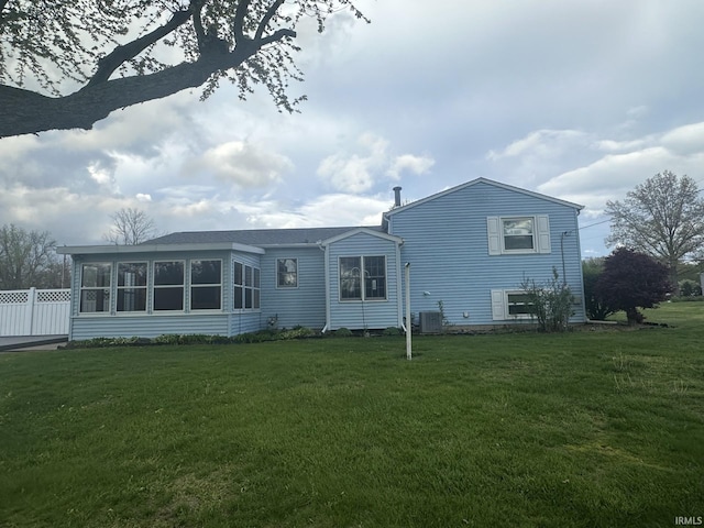 rear view of house featuring fence, a yard, central AC unit, and a sunroom