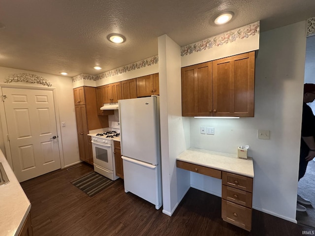 kitchen with built in study area, a textured ceiling, dark wood finished floors, and white appliances