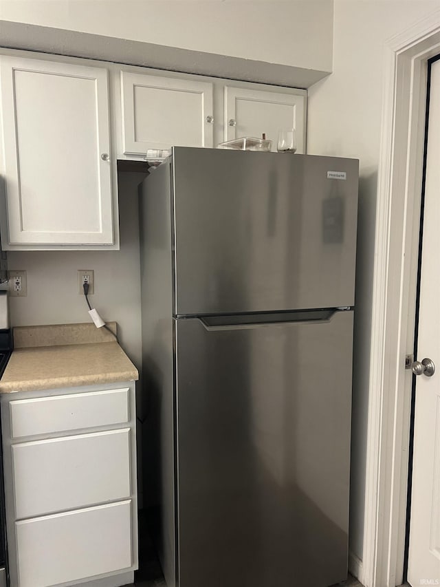 kitchen with light countertops, freestanding refrigerator, and white cabinetry