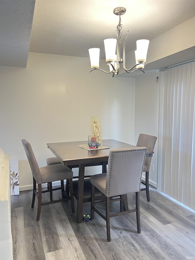 dining room with baseboards, an inviting chandelier, and wood finished floors