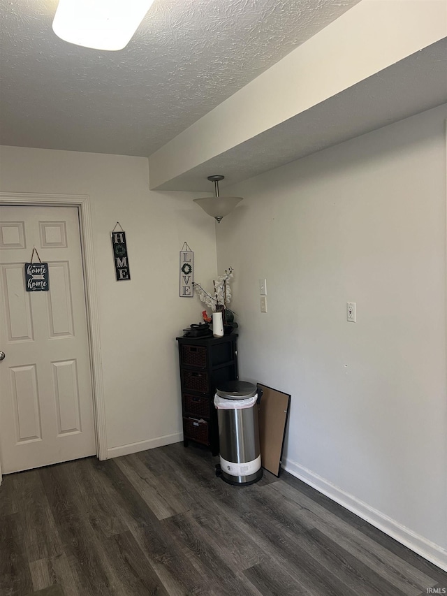 foyer entrance featuring a textured ceiling, dark wood-style floors, and baseboards