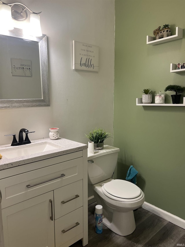 bathroom featuring vanity, baseboards, toilet, and wood finished floors