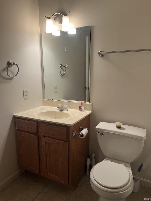 half bathroom with vanity, baseboards, tile patterned flooring, and toilet