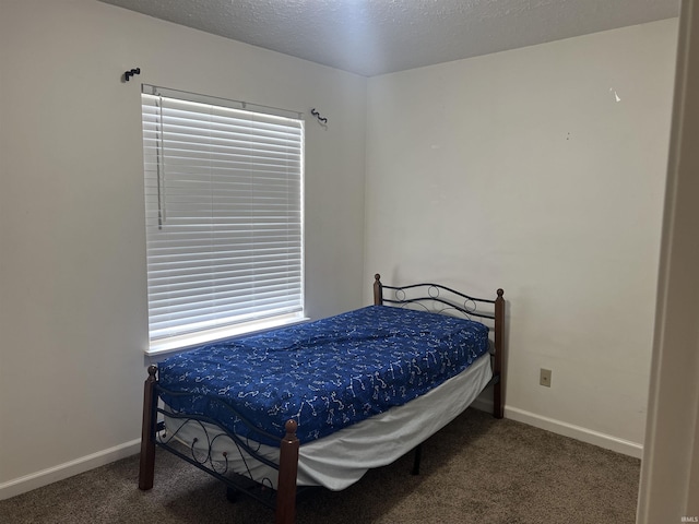 carpeted bedroom featuring baseboards and a textured ceiling