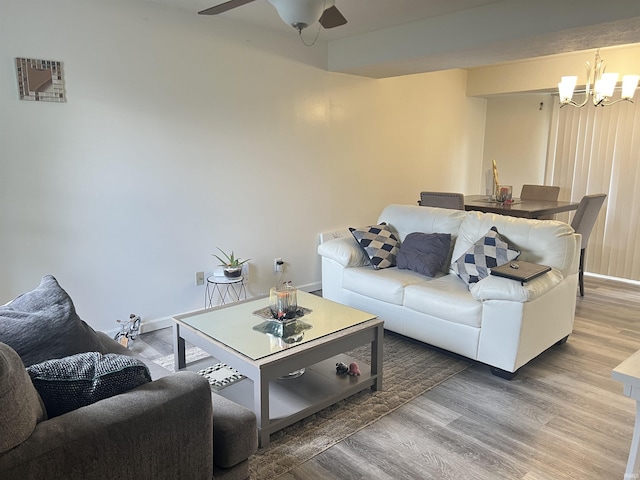 living area featuring baseboards, ceiling fan with notable chandelier, and wood finished floors