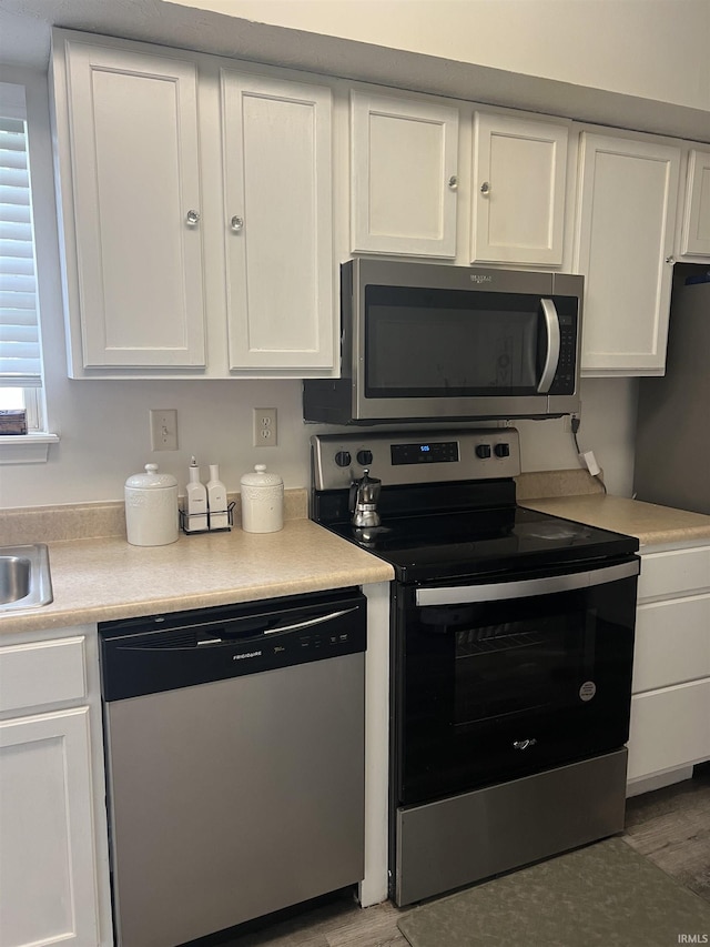 kitchen featuring light countertops, appliances with stainless steel finishes, white cabinets, and wood finished floors