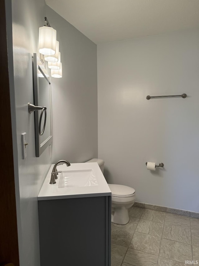 half bath featuring toilet, baseboards, and vanity