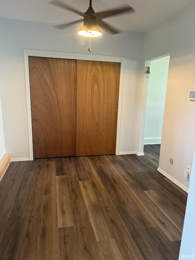 unfurnished bedroom with baseboards, ceiling fan, a closet, and dark wood-type flooring