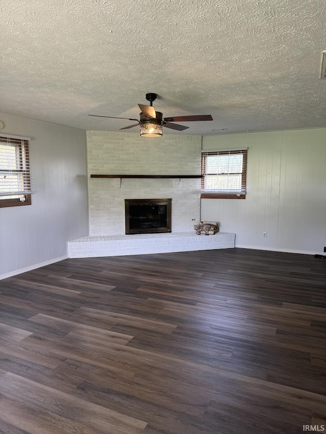 unfurnished living room featuring a fireplace, a ceiling fan, a textured ceiling, and wood finished floors