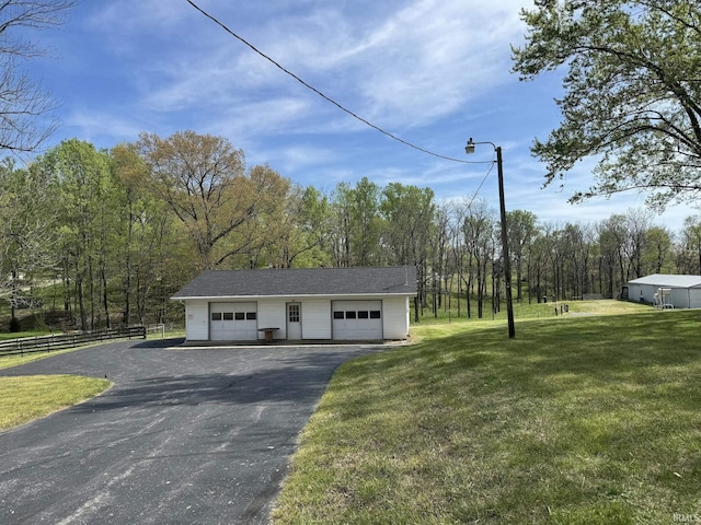 detached garage with fence, a view of trees, and aphalt driveway