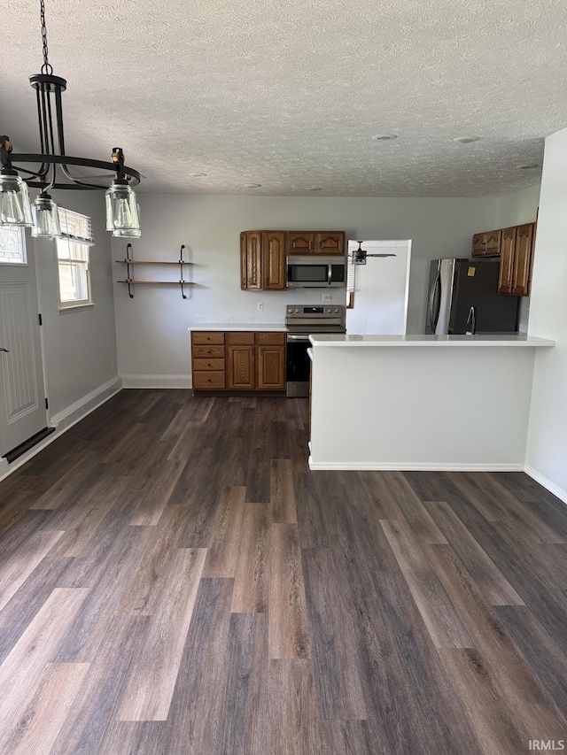 kitchen featuring baseboards, dark wood-style floors, light countertops, a textured ceiling, and stainless steel appliances