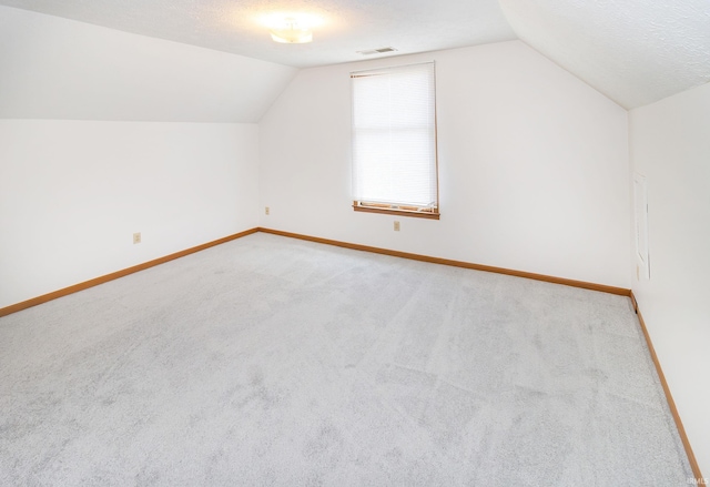 bonus room with baseboards, visible vents, light colored carpet, and lofted ceiling