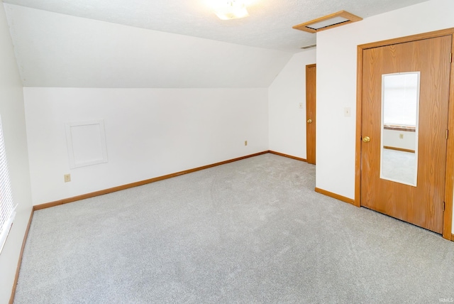 additional living space featuring baseboards, light carpet, attic access, and lofted ceiling