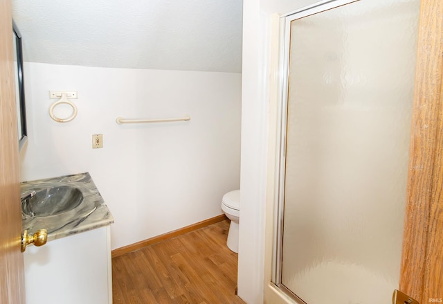 full bathroom featuring vanity, toilet, baseboards, wood finished floors, and a stall shower