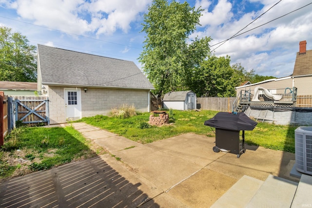 view of patio with a deck, an outbuilding, cooling unit, a fenced backyard, and a storage unit