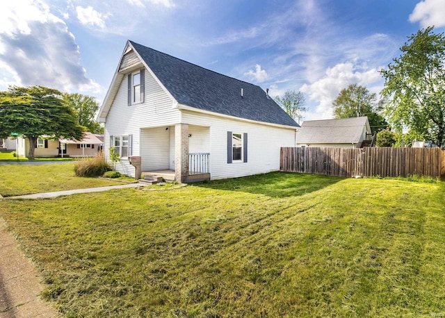 view of home's exterior with a lawn, fence, and a shingled roof
