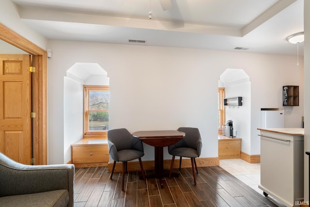 living area with arched walkways, visible vents, and wood finished floors