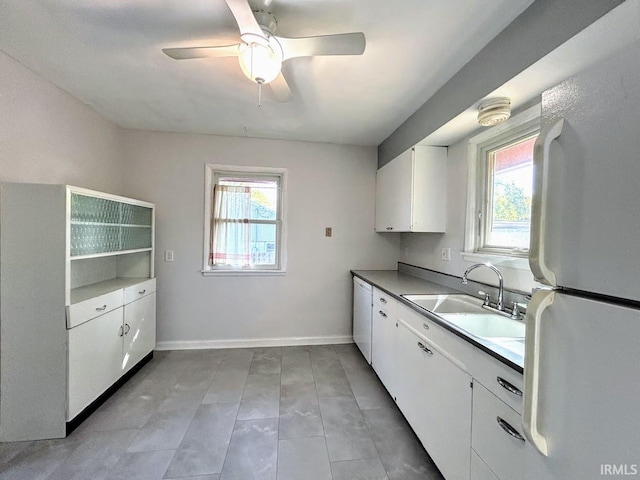 kitchen featuring a sink, white appliances, white cabinetry, a ceiling fan, and baseboards