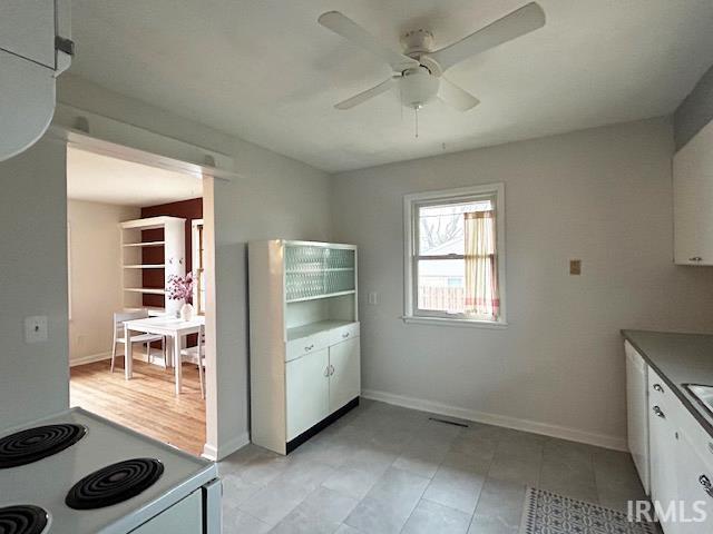 kitchen featuring baseboards, white range with electric cooktop, ceiling fan, and white cabinets