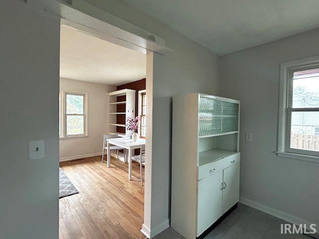 clothes washing area with baseboards and wood finished floors