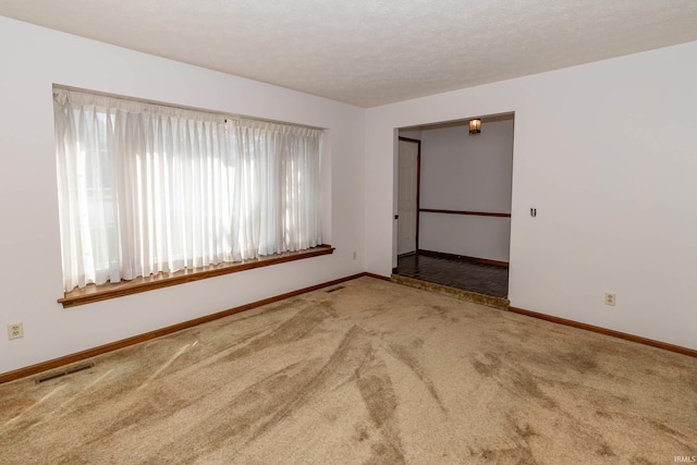 spare room with baseboards, carpet flooring, and visible vents