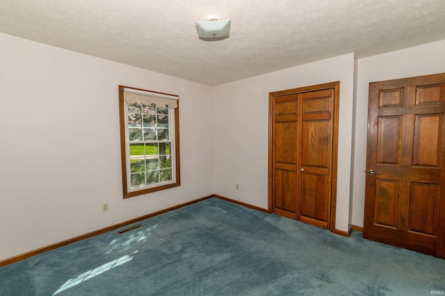 unfurnished bedroom featuring a textured ceiling, carpet, baseboards, visible vents, and a closet