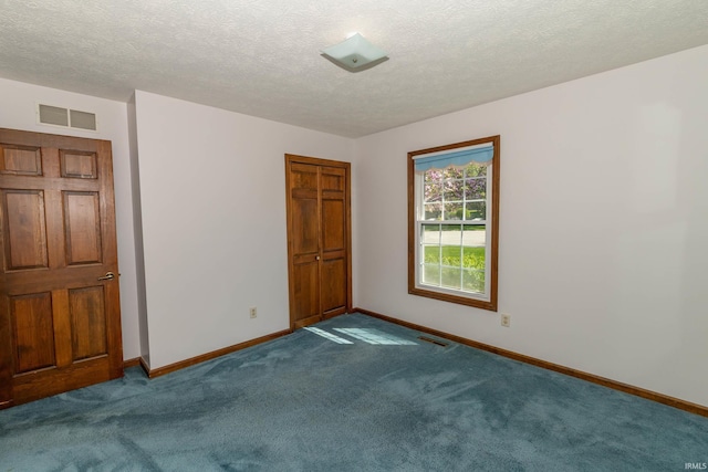 carpeted empty room with a textured ceiling, baseboards, and visible vents