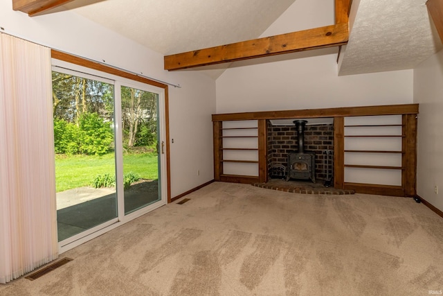 unfurnished living room featuring lofted ceiling with beams, carpet, a wood stove, and visible vents