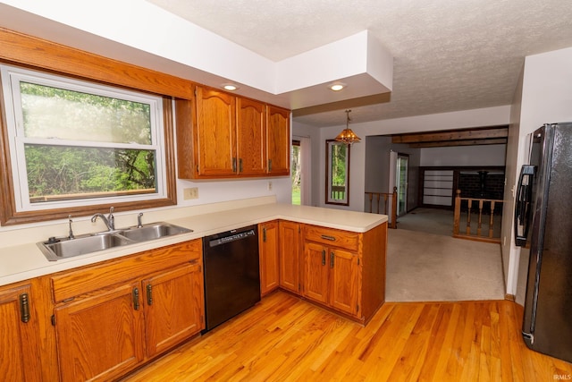 kitchen featuring a peninsula, a healthy amount of sunlight, a sink, and black appliances