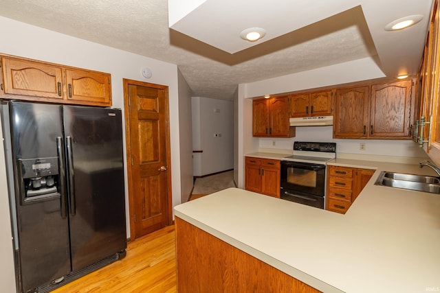 kitchen featuring range with electric stovetop, black fridge with ice dispenser, a sink, light wood-style floors, and under cabinet range hood
