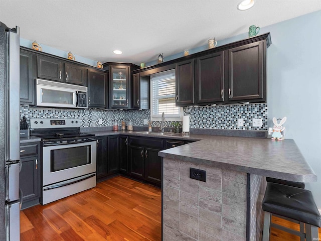 5326 Dennison Dr, Fort Wayne, IN 46835 - kitchen with appliances with stainless steel finishes, dark countertops, wood finished floors, a sink, and a peninsula