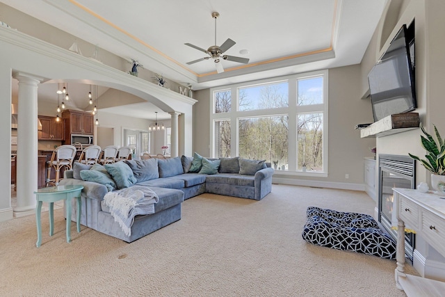 living area featuring ornate columns, arched walkways, a ceiling fan, and light carpet