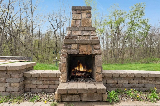 exterior space featuring an outdoor stone fireplace and a forest view