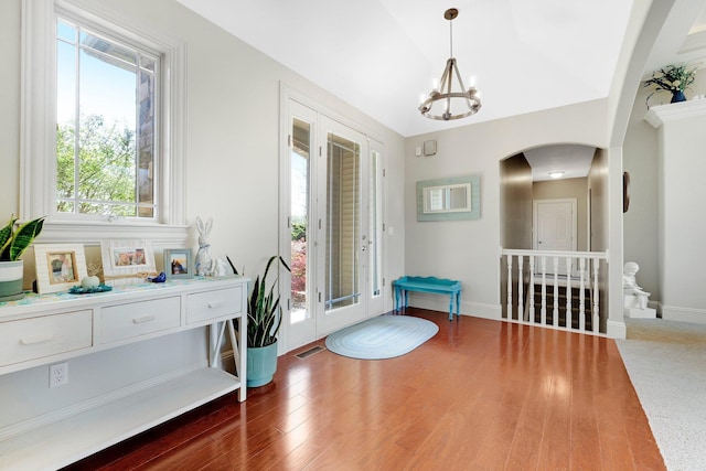 interior space featuring arched walkways, visible vents, wood finished floors, and a notable chandelier