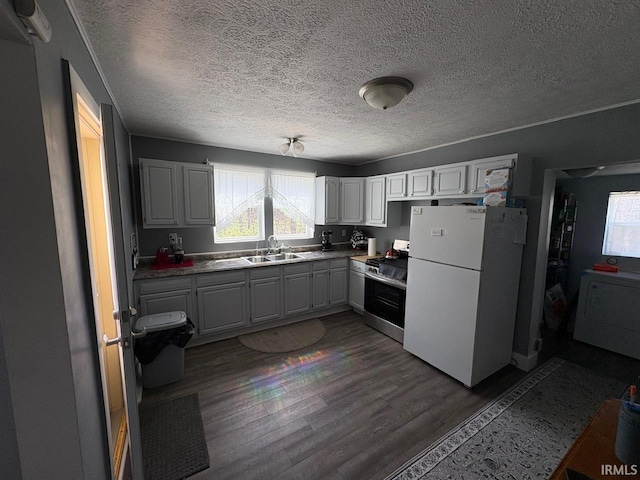 kitchen with stainless steel range, a textured ceiling, freestanding refrigerator, washer / clothes dryer, and wood finished floors