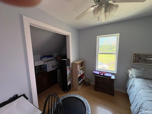 bedroom with a ceiling fan, a textured ceiling, and wood finished floors
