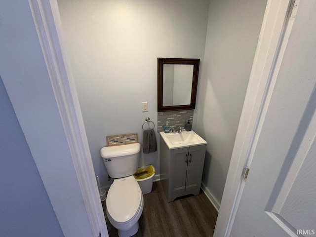 bathroom featuring toilet, baseboards, wood finished floors, and vanity
