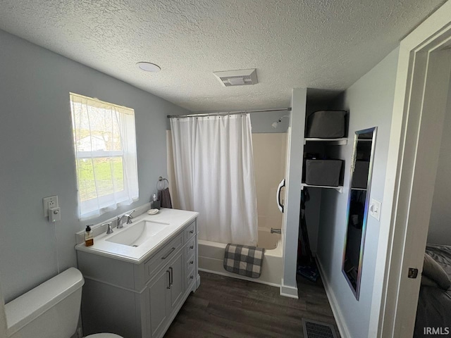full bath with vanity, toilet, a textured ceiling, wood finished floors, and visible vents