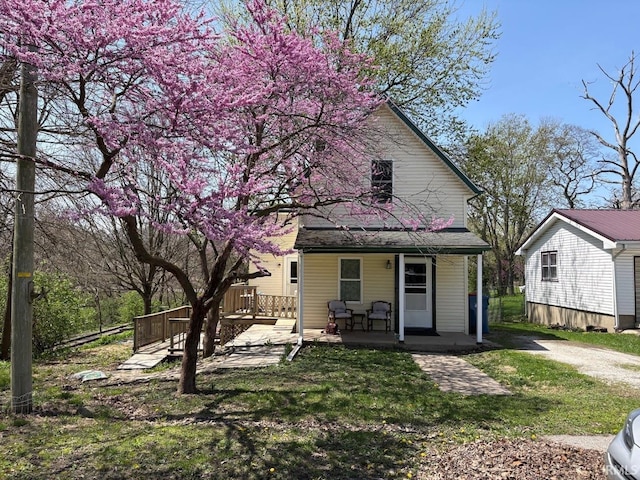 rear view of house featuring a yard and covered porch