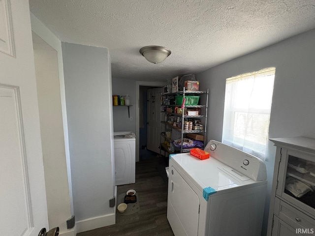 clothes washing area featuring laundry area, a textured ceiling, washing machine and clothes dryer, baseboards, and dark wood-type flooring