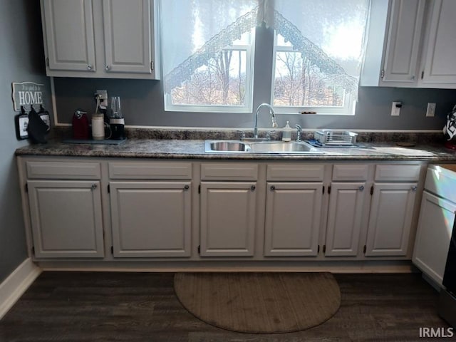 kitchen with white cabinets, dark countertops, a wealth of natural light, and a sink