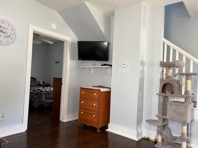 interior space with a textured ceiling, baseboards, and dark wood-type flooring