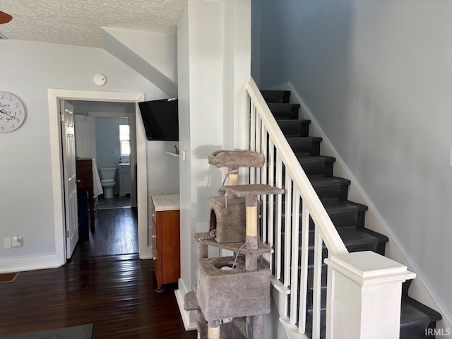 stairs featuring wood-type flooring, a textured ceiling, and baseboards