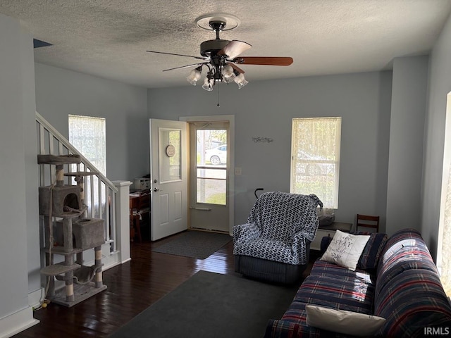 living area featuring a healthy amount of sunlight, a ceiling fan, stairs, and wood finished floors