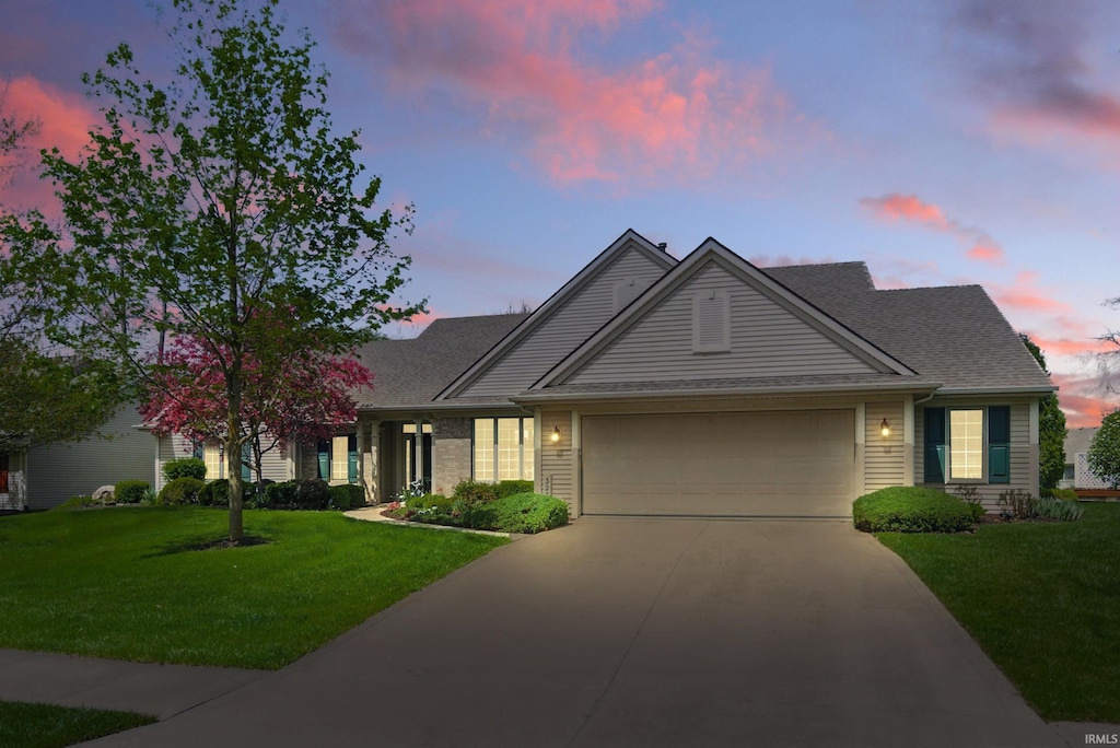 view of front of home with a yard, driveway, and a garage